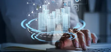 Osoba używająca komputera, z przodu grafika przedstawiająca wizualizację miasta z technologiami